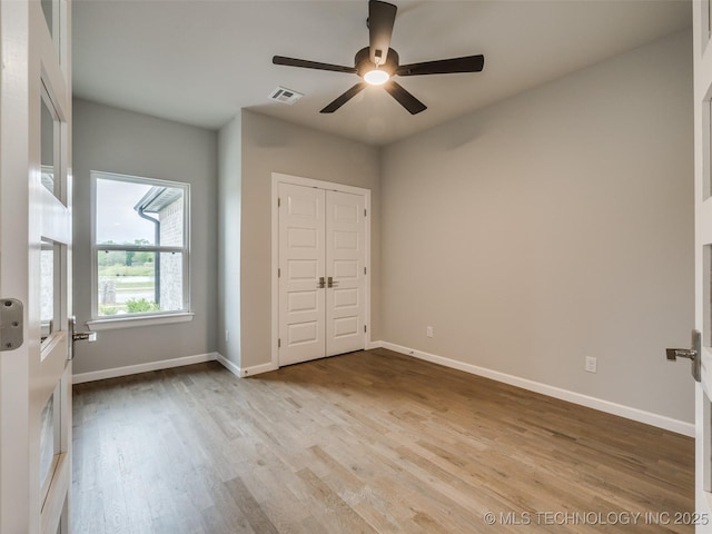 unfurnished bedroom with baseboards, a ceiling fan, wood finished floors, and visible vents