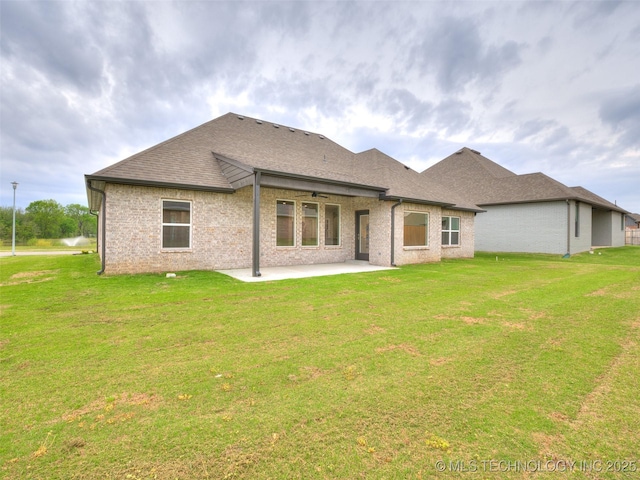 rear view of property featuring a patio area, roof with shingles, a ceiling fan, and a lawn