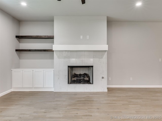 unfurnished living room featuring a tile fireplace, baseboards, wood finished floors, and recessed lighting