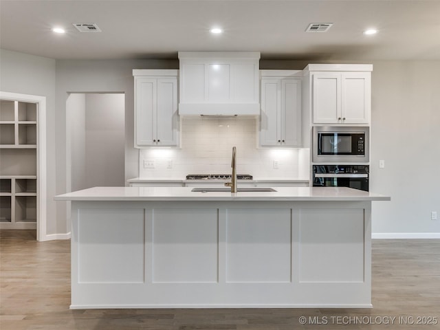 kitchen with built in microwave, light countertops, stainless steel oven, and visible vents