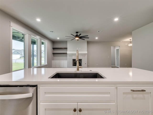 kitchen with light countertops, a sink, white cabinetry, ceiling fan, and dishwasher