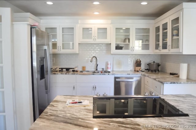 kitchen with sink, white cabinetry, light stone counters, stainless steel appliances, and backsplash