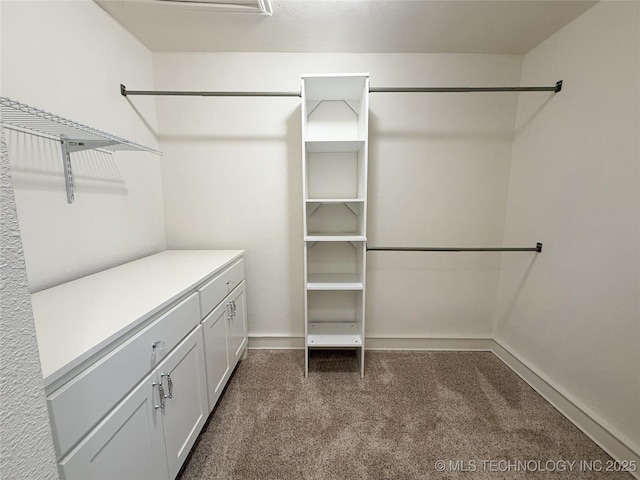 walk in closet with dark colored carpet