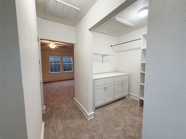 walk in closet with light carpet and ceiling fan