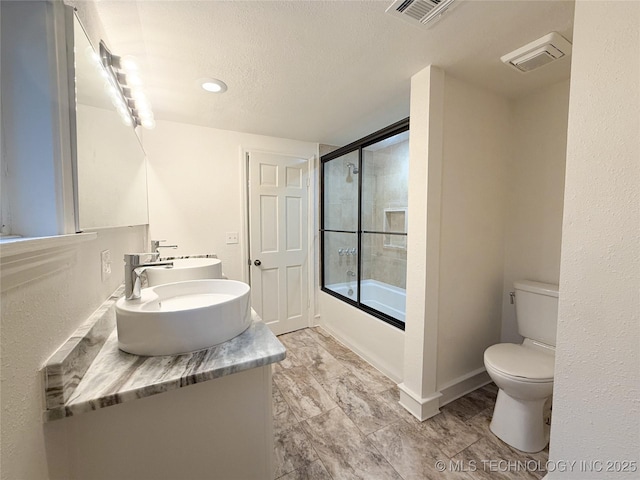 full bathroom featuring vanity, a textured ceiling, toilet, and combined bath / shower with glass door