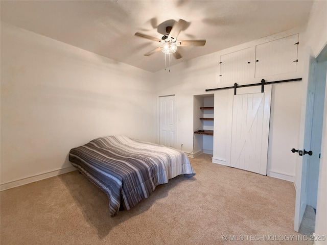 carpeted bedroom featuring a barn door and ceiling fan