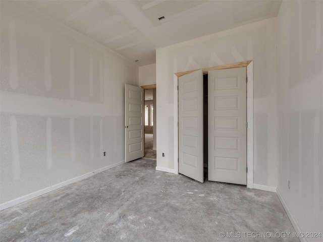 unfurnished bedroom featuring concrete flooring and a closet