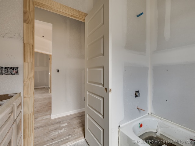 bathroom with hardwood / wood-style flooring and a bath