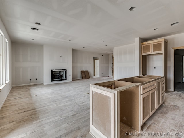 kitchen with light brown cabinetry, a center island, and light wood-type flooring