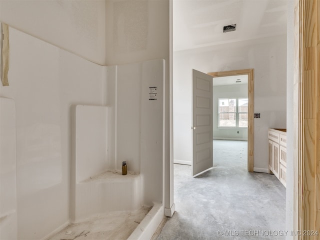 bathroom featuring concrete flooring, vanity, and walk in shower