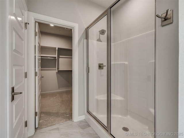 bathroom featuring a shower stall, a spacious closet, and marble finish floor