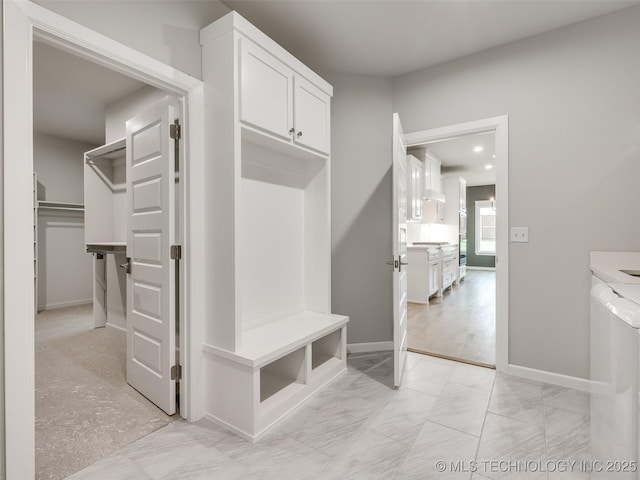 mudroom featuring marble finish floor, baseboards, and washer / clothes dryer