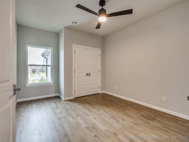 unfurnished bedroom featuring wood finished floors, visible vents, and baseboards