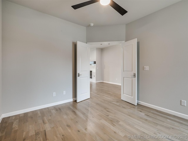 unfurnished room with baseboards, a ceiling fan, and light wood-type flooring