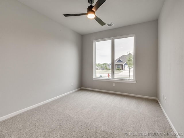 unfurnished room featuring light colored carpet, baseboards, a ceiling fan, and visible vents