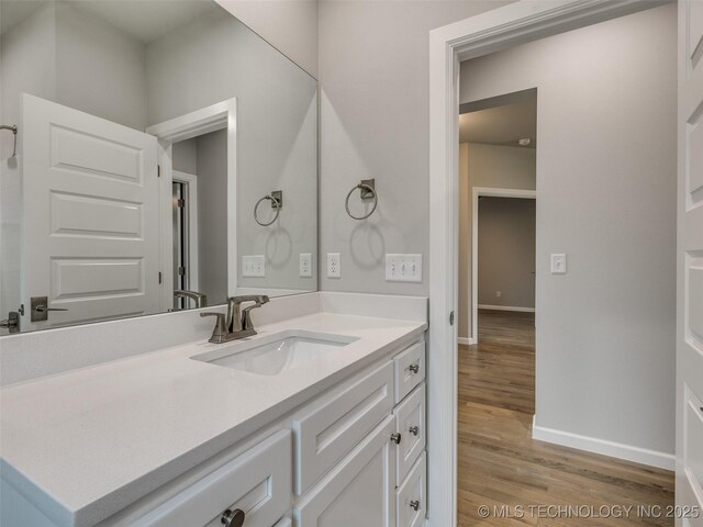 bathroom featuring baseboards, wood finished floors, and vanity