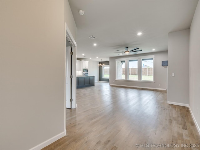 unfurnished living room featuring ceiling fan with notable chandelier, light wood-style flooring, baseboards, visible vents, and recessed lighting