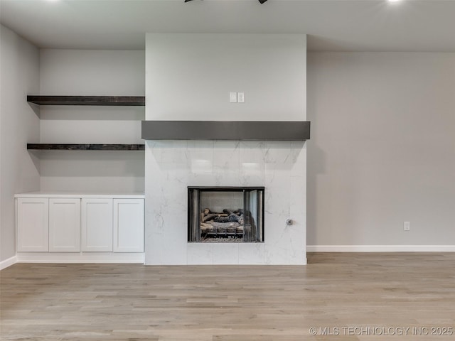 unfurnished living room with a fireplace, wood finished floors, and baseboards