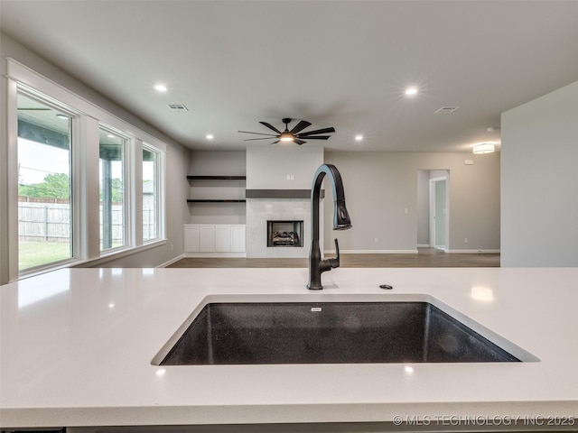 kitchen featuring ceiling fan, open floor plan, a sink, and visible vents
