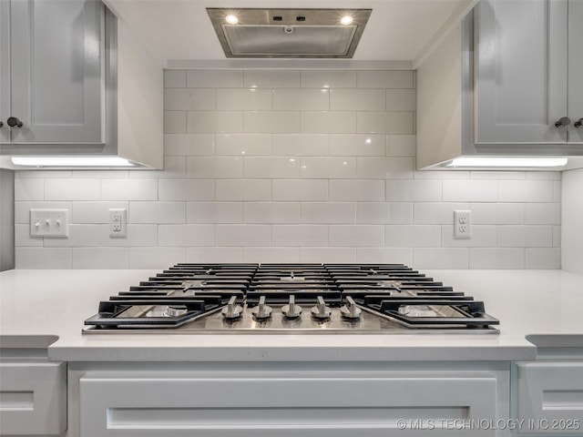 kitchen with decorative backsplash, stainless steel gas cooktop, light countertops, and wall chimney range hood