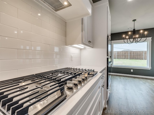 kitchen with stainless steel gas stovetop, backsplash, and white cabinets