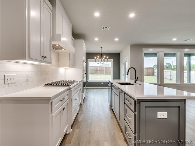 kitchen featuring light countertops, visible vents, a sink, and white cabinetry