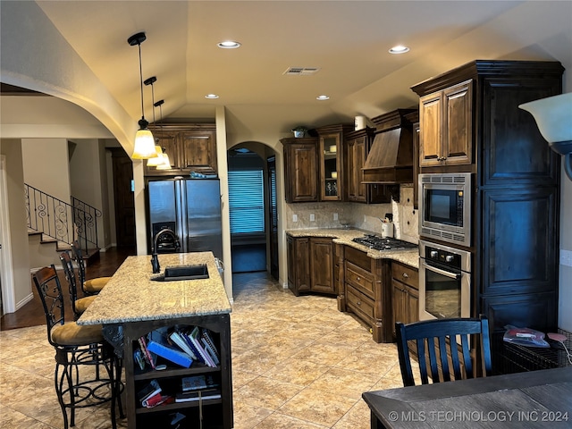 kitchen featuring lofted ceiling, backsplash, premium range hood, sink, and stainless steel appliances