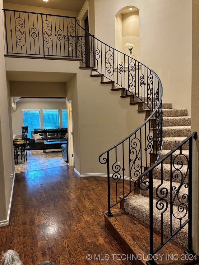 stairs with wood-type flooring and a high ceiling