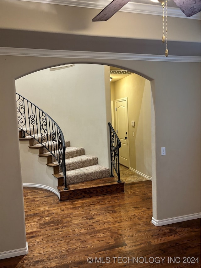 stairs featuring wood-type flooring and ornamental molding