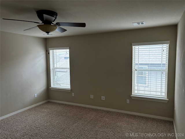 carpeted spare room featuring ceiling fan and a healthy amount of sunlight