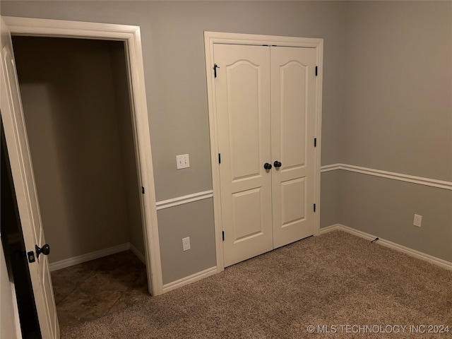 unfurnished bedroom with dark carpet and a closet