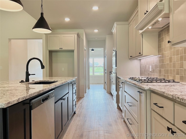 kitchen with appliances with stainless steel finishes, custom exhaust hood, light stone counters, and pendant lighting