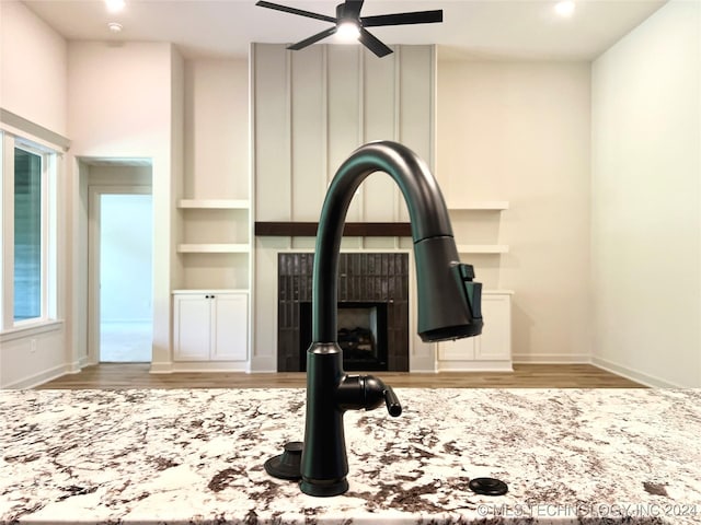 room details with ceiling fan, a tile fireplace, baseboards, light wood-type flooring, and light stone countertops