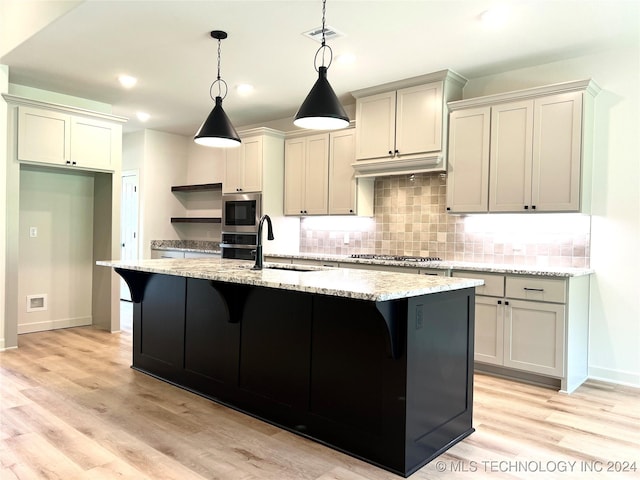 kitchen featuring hanging light fixtures, an island with sink, a sink, and stainless steel appliances