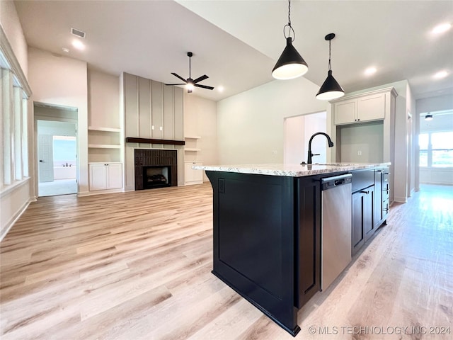 kitchen featuring white cabinets, decorative light fixtures, a kitchen island with sink, stainless steel dishwasher, and a sink