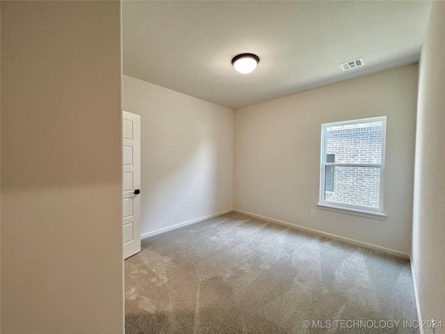 spare room with visible vents, light carpet, and baseboards