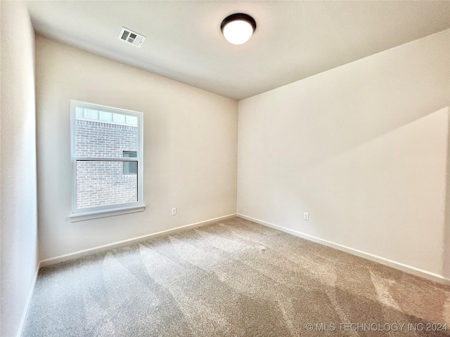 empty room featuring carpet, visible vents, and baseboards