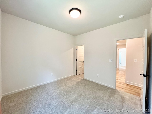 unfurnished bedroom with light colored carpet and baseboards