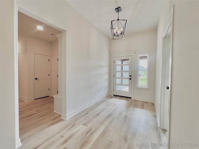 foyer with light wood-style floors, baseboards, and a chandelier