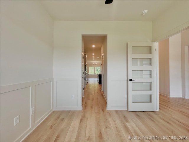 empty room featuring a wainscoted wall, light wood-type flooring, built in features, and a decorative wall