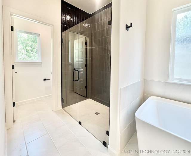 full bathroom featuring tile patterned floors, a freestanding tub, tile walls, and a shower stall