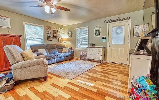 living room with light hardwood / wood-style floors, an AC wall unit, plenty of natural light, and ceiling fan