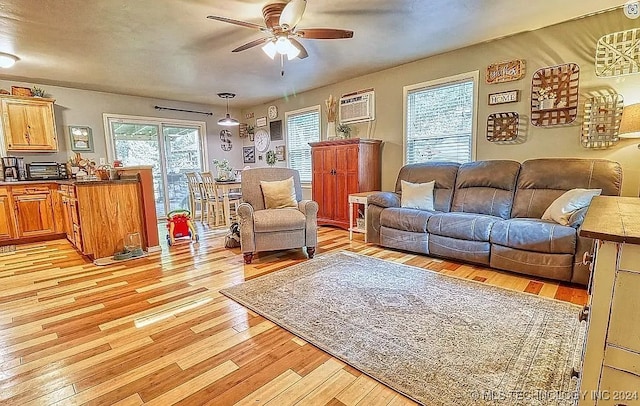 living room with ceiling fan, light hardwood / wood-style floors, and a wall unit AC