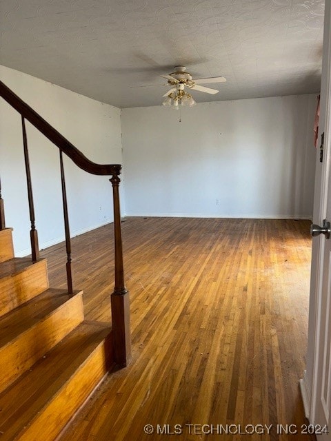 stairs featuring hardwood / wood-style floors and ceiling fan