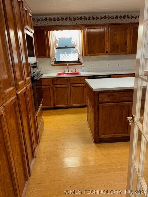 kitchen with light hardwood / wood-style floors, oven, and sink