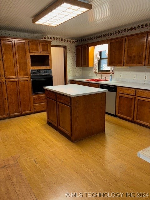 kitchen with light wood-type flooring, stainless steel dishwasher, sink, oven, and a kitchen island