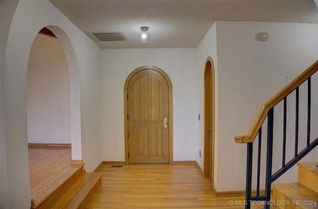 17808 S 129th E Ave, Bixby, OK 74008 - entrance foyer with light wood-style floors, stairs, a textured ceiling, and arched walkways