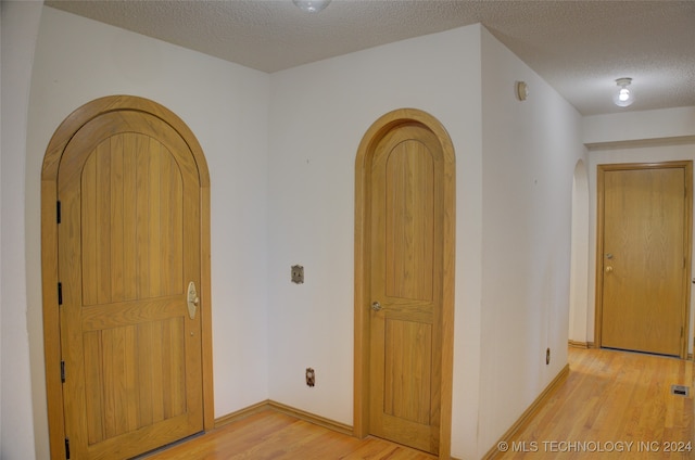 corridor featuring light hardwood / wood-style flooring and a textured ceiling