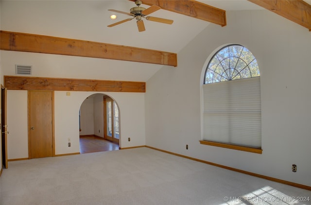 unfurnished room with ceiling fan, lofted ceiling with beams, and light carpet