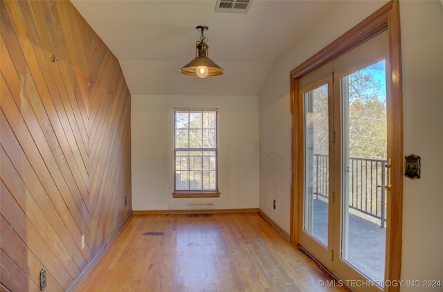 spare room featuring wooden walls, light hardwood / wood-style flooring, and a healthy amount of sunlight